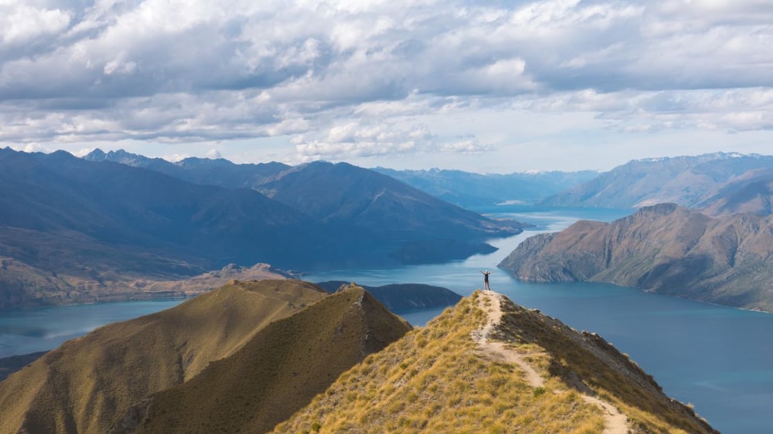 hiker reaching the summit of a mountain trail